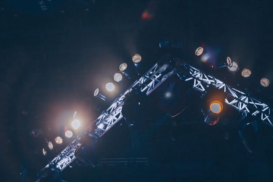Stage lighting mounted on an aluminium truss, seen from below against a dark ceiling.