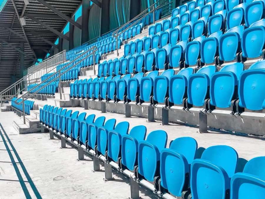Empty tiered stadium seating under a covered stand, before spectators arrive.